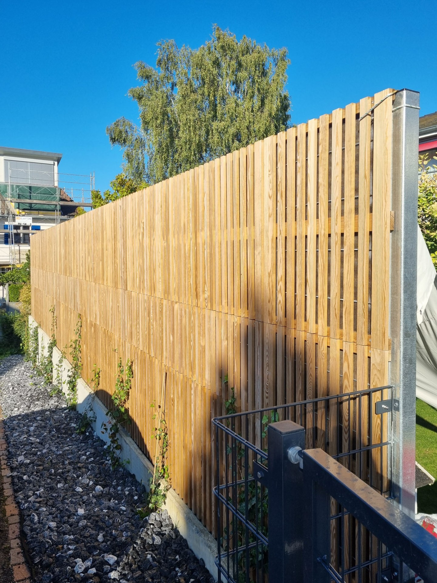 Close-up of a Noistop Essential barrier with vertical wooden slats and galvanised steel post