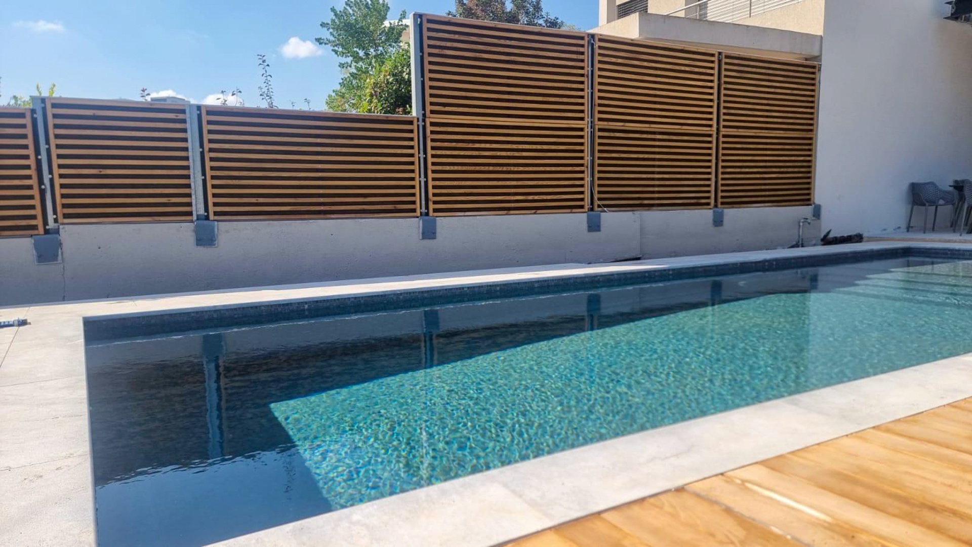 Noistop Wood wooden barrier along a private swimming pool with a white wall in the background