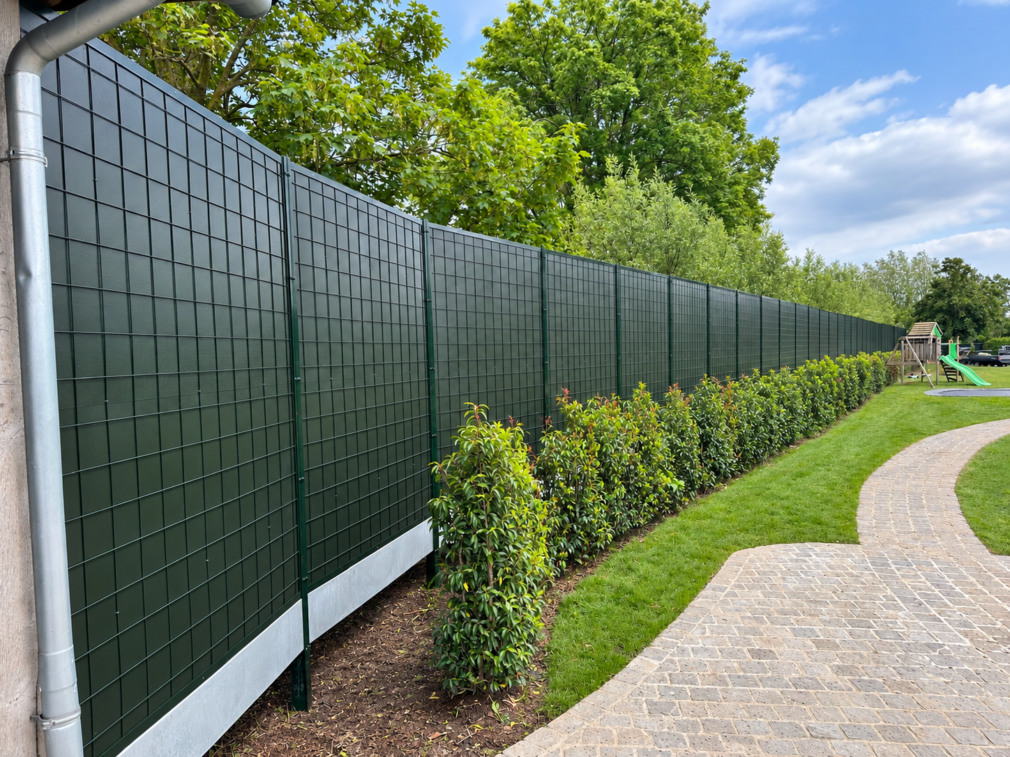 Green Noise-Reducer sound barrier along a landscaped garden with a path and planting