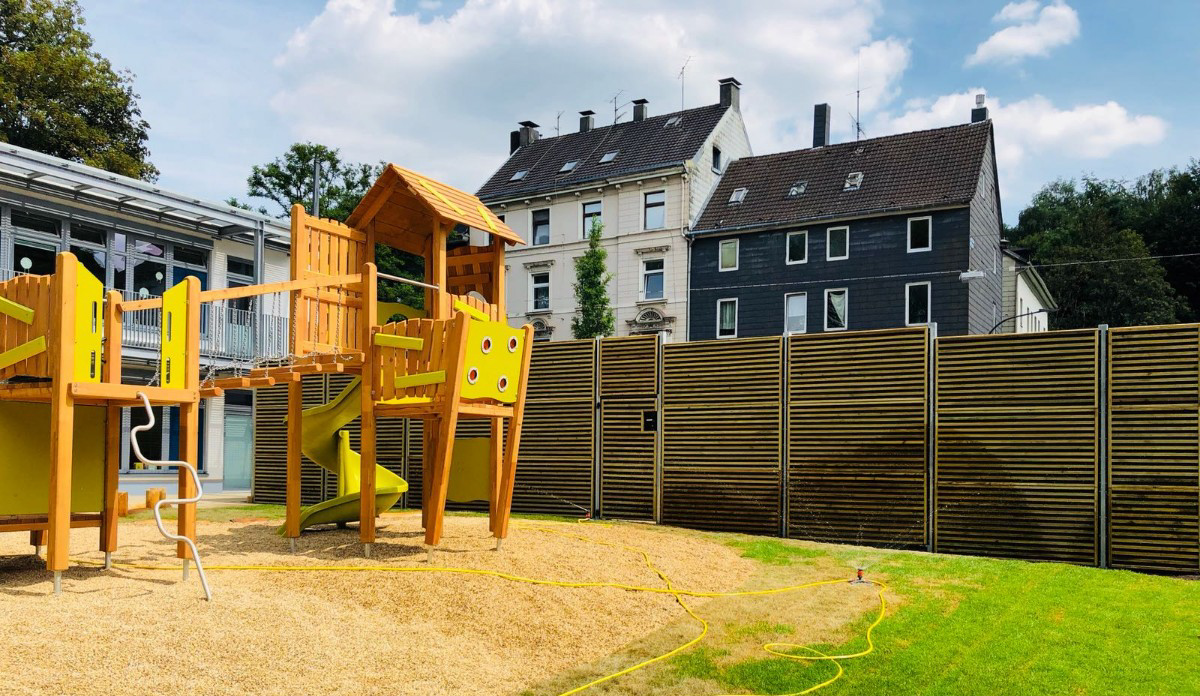 Noistop Wood wooden noise barrier surrounding a colourful playground at a German kindergarten