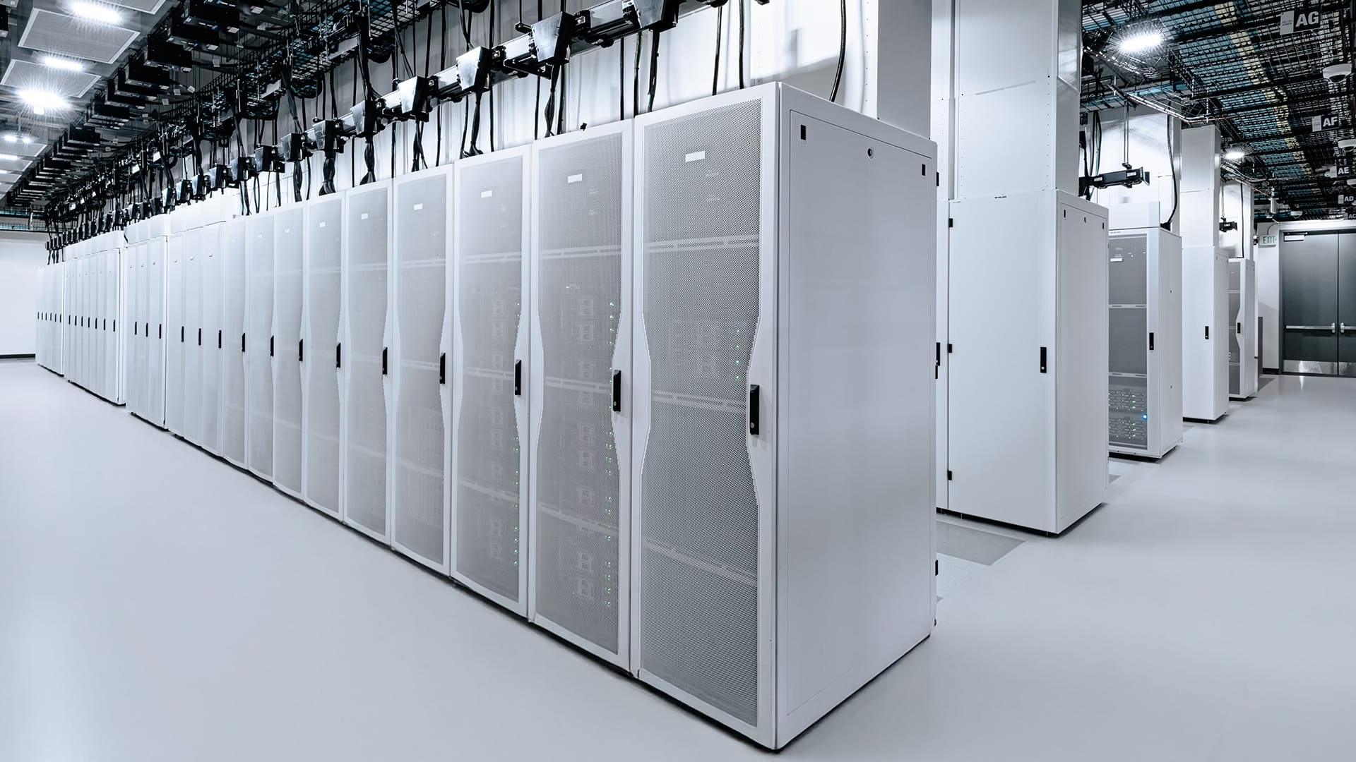 Serverruimte in een datacenter met rijen witte serverracks en koelinstallatie