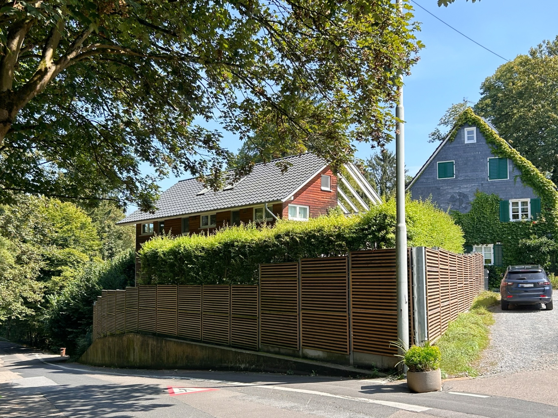 Long Noistop Wood barrier along a residential street lined with trees
