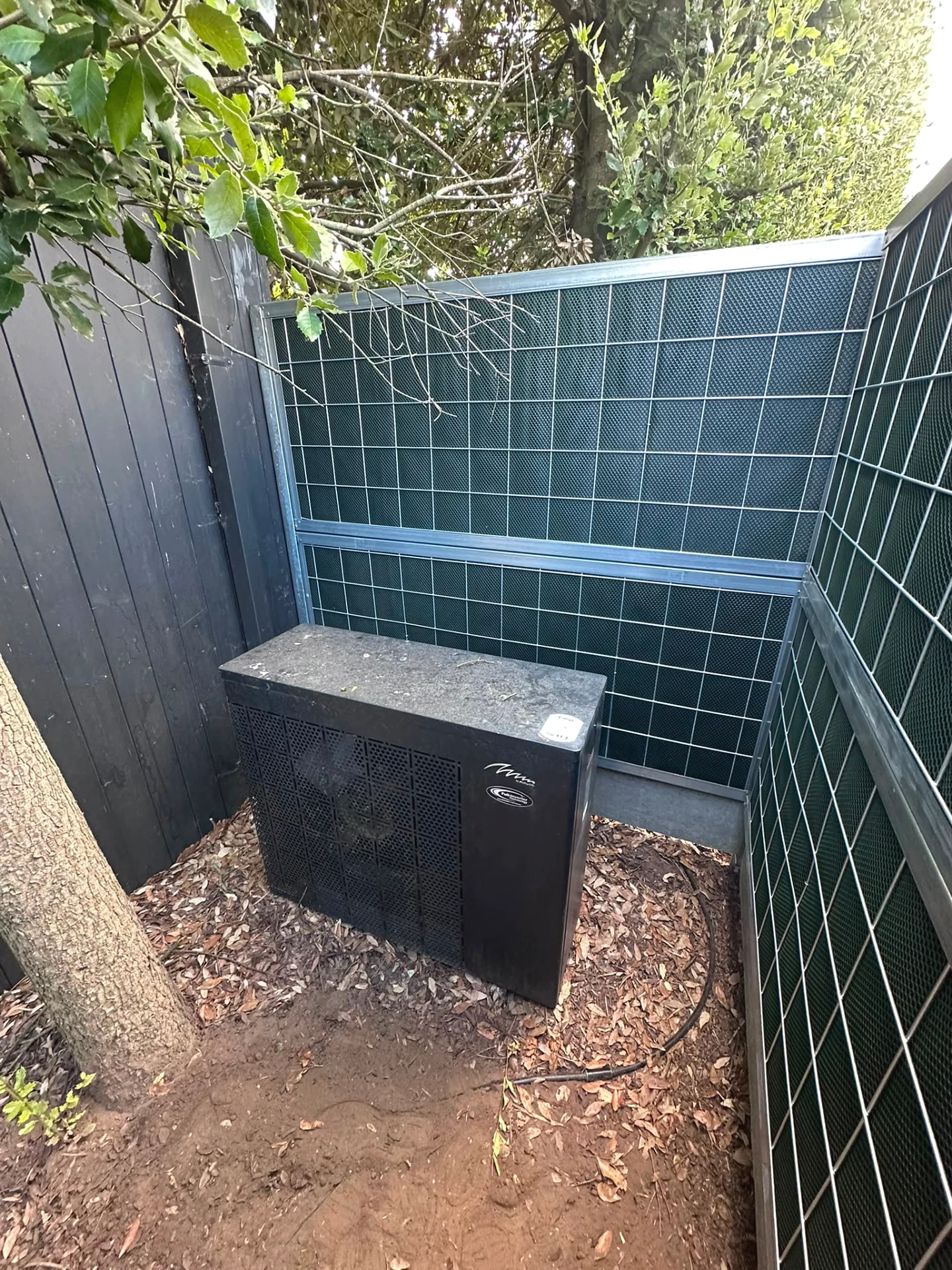 Warmtepomp tussen Noise-Reducer schermen in een tuin