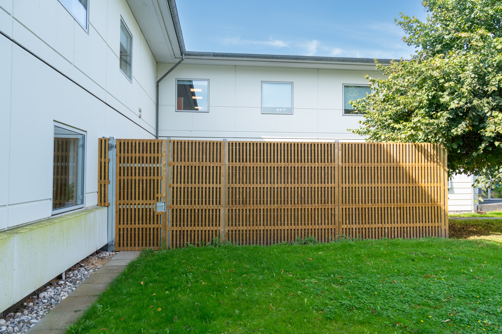 Noistop Essential noise barrier with wooden slats and galvanised steel posts next to a municipal building in Denmark