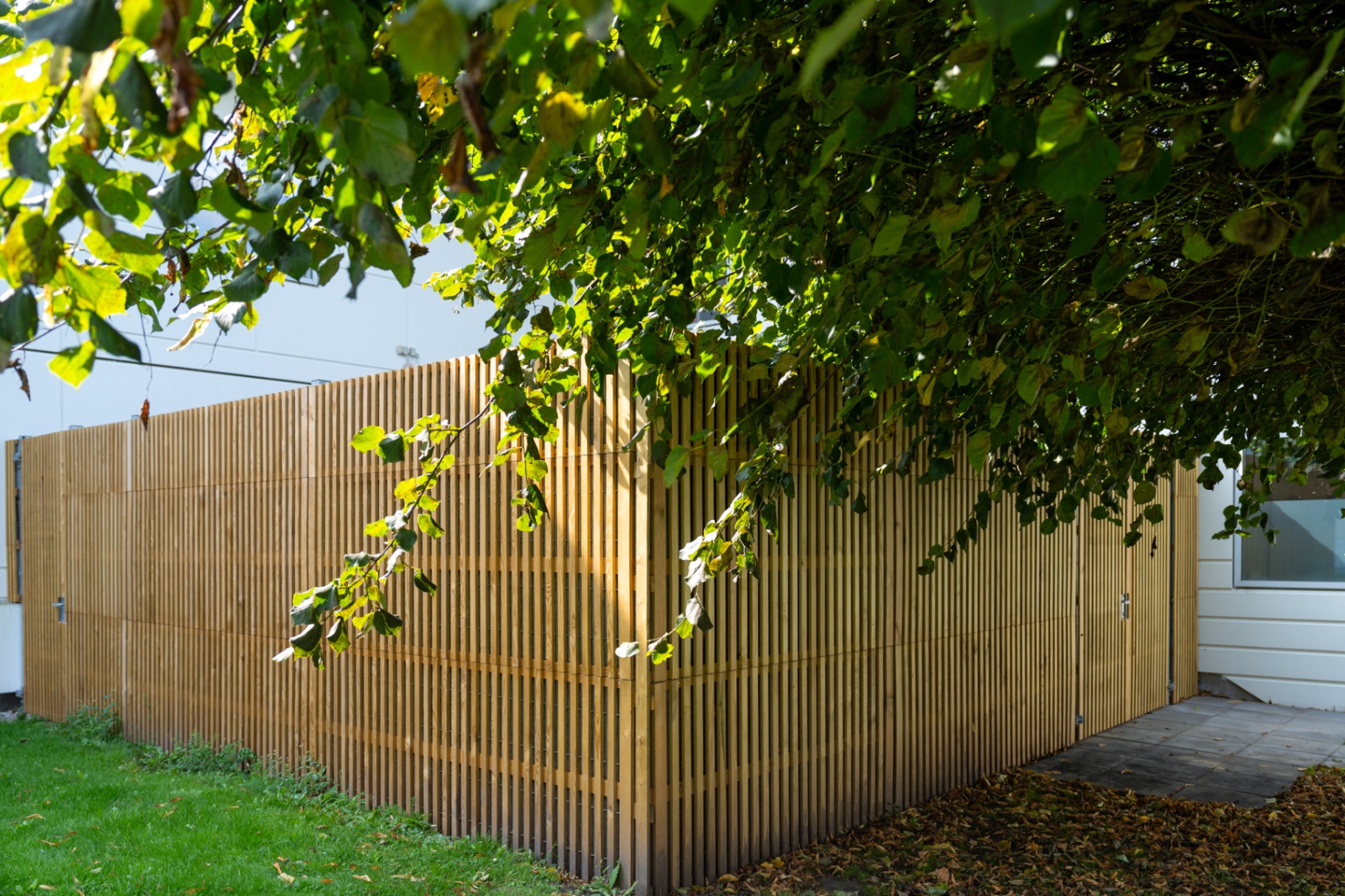 Noistop Essential with wooden cladding screening a municipal building in Denmark, under a tree