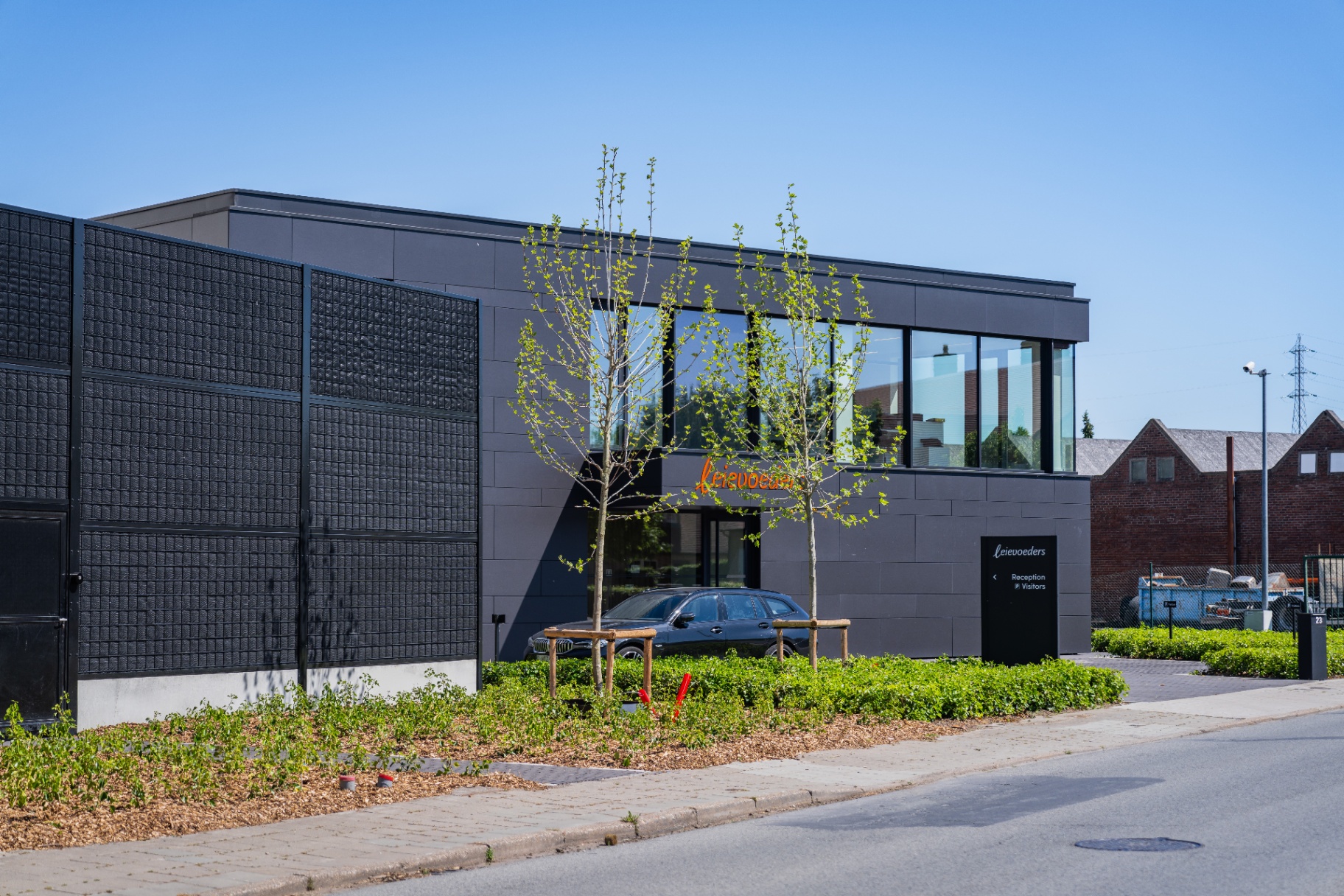 Noise-Reducer sound barrier along the Leievoeders facade in Waregem, dark panels blending with the modern industrial architecture