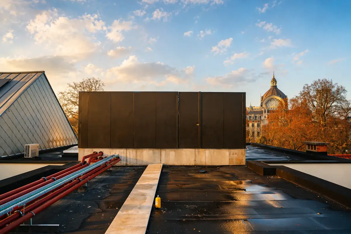 Mur antibruit Ichono Wall sur un toit à Anvers avec panneaux profilés sombres et vue sur la coupole de la gare centrale au coucher du soleil