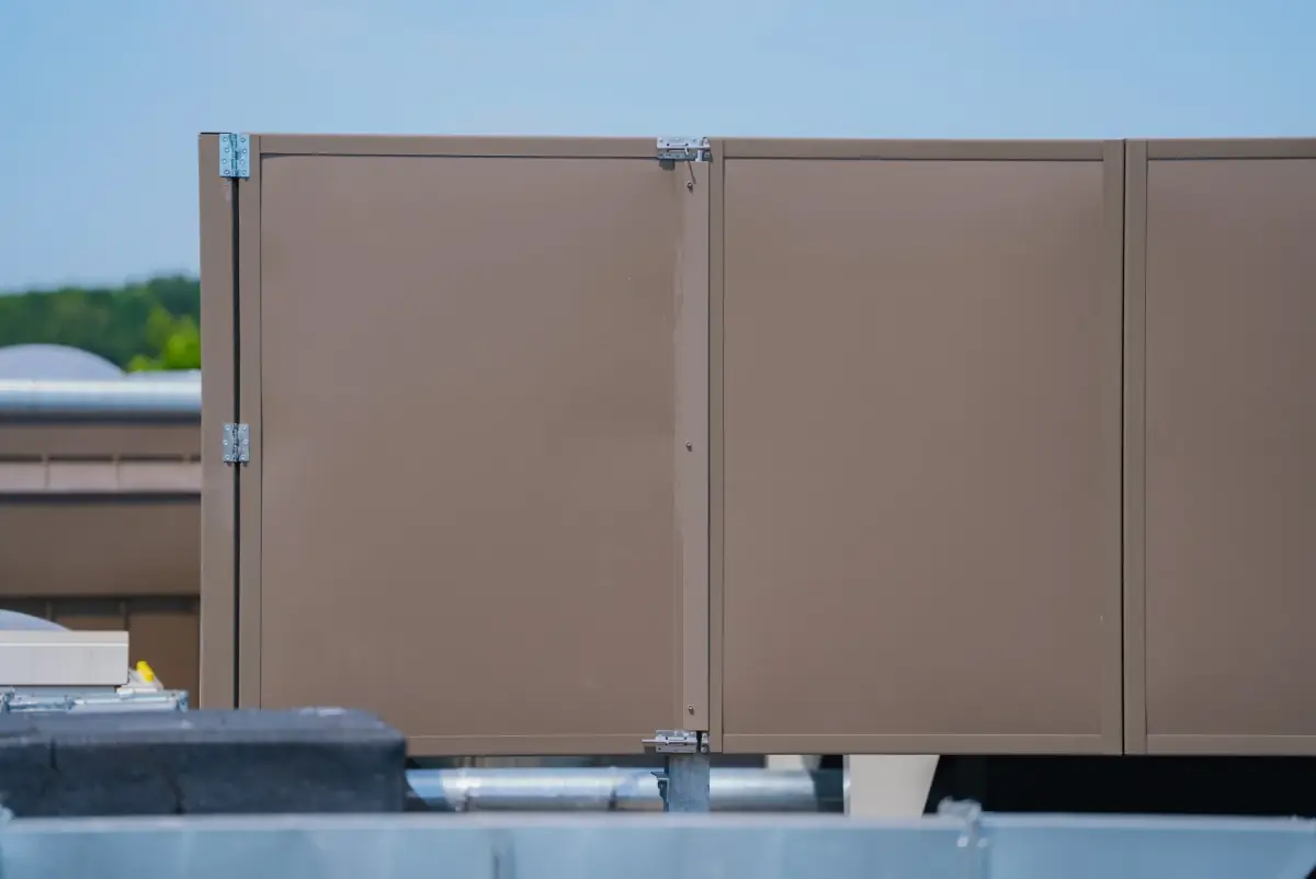 Noise-Reducer sound barrier around heat pumps on a flat roof, overlooking a green environment