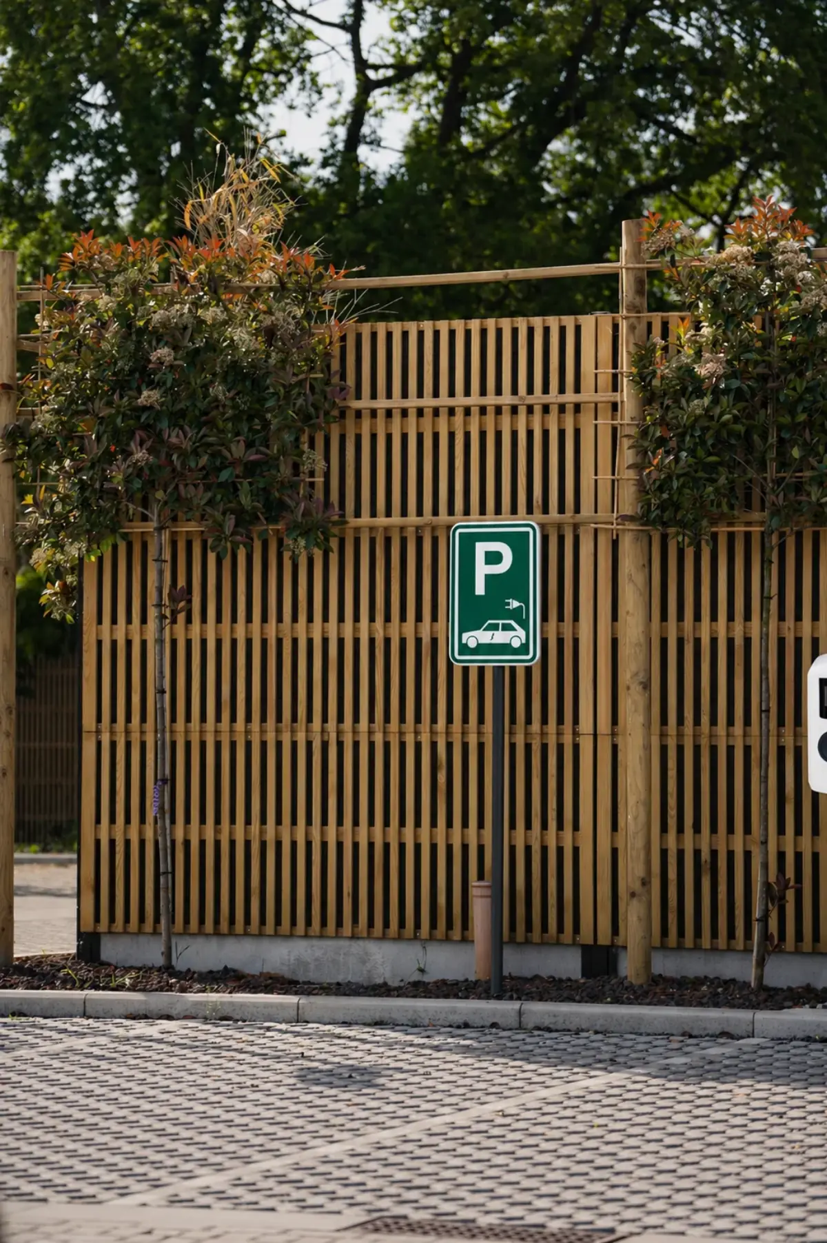Noise-Reducer Wood sound barrier along a parking area with integrated trees, shown in the actual natural wood tone