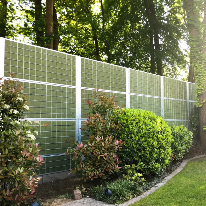 Noistop Steel sound barrier with PE netting finish and green shrubs in a residential setting