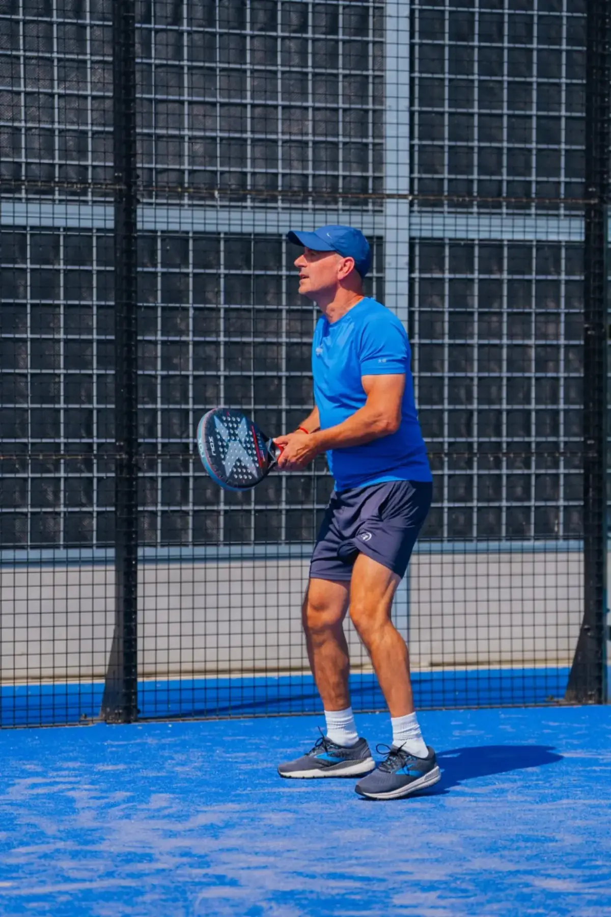 Padel player in action with sound-reducing back wall, effective noise reduction for sports clubs